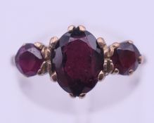 A 9 ct gold three-stone garnet ring. Ring size P. 2.3 grammes total weight.