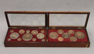 A fitted mahogany display cabinet containing a collection of copper castings of various medallions.