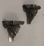 Two parian black-painted cherub wall brackets. Each 18 cm high.