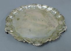 A silver salver engraved with initials. 25 cm diameter. 574.8 grammes.