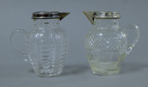 Two unmarked silver rimmed glass jugs. Each 9.5 cm high.