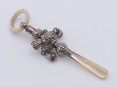 A silver and mother-of-pearl baby rattle with teething ring. 11 cm high.