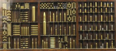 A wall hanging cased display of inert bullet shells. 82 cm wide.