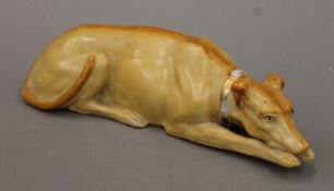A Staffordshire pottery figure of a recumbent greyhound. 22 cm long.
