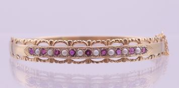 A 9 ct gold, seed pearl and garnet bracelet. 5.8 cm internal diameter, 8 mm high. 13.