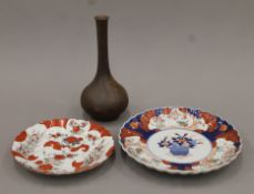 A Japanese pottery bottle vase with incised signature and two Imari plates. The former 26 cm high.
