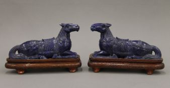 A pair of Chinese carved lapis lazuli recumbent horses each standing on a wooden plinth base.