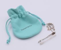 A Tiffany & Co silver chain and a small pair of Tiffany & Co silver tongs.