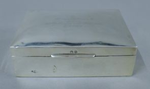 A silver cigarette box with presentation inscription. 11.5 cm wide.