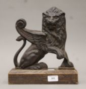 A cast iron winged lion doorstop mounted on a wooden plinth base. 29 cm high.