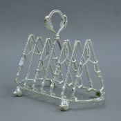 A silver-plated toast rack formed as riding crops and fox masks. 20.5 cm long.