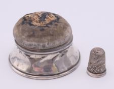 A silver pin cushion box and a cased silver thimble. Pin cushion 6.3 cm diameter at base, thimble 2.