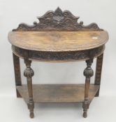 A Victorian carved oak demi-lune side table. 91 cm wide.
