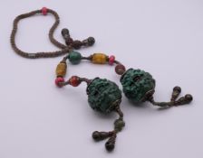 A Tibetan string of prayer beads with two large green spheres and multi-coloured beads.