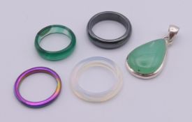 A silver and jade pendant together with four rings. Pendant 4 cm high including suspension loop.