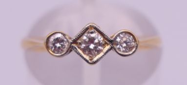 An 18 ct gold three-stone diamond ring. Ring size L/M. 1.6 grammes total weight.