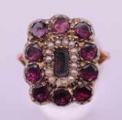 A Georgian gold, garnet and seed pearl mourning ring. Ring size R/S. 6.3 grammes total weight.