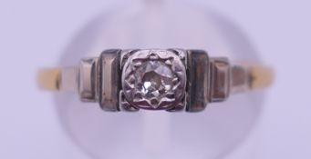 An 18 ct gold and platinum diamond solitaire ring with stepped shoulders. Ring size R. 2.