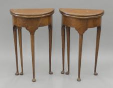 A pair of mahogany demi-lune fold over side tables. Each 45 cm wide.