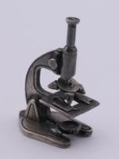 A silver miniature microscope. 4.5 cm high.