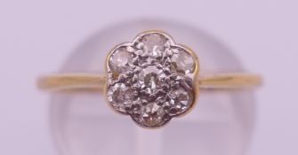 An unmarked 18 ct gold diamond flowerhead ring. Ring size O/P. 1.8 grammes total weight.