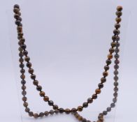 A tiger's eye bead necklace. Approximately 92 cm long, beads approximately 7 mm diameter.