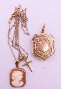 A small 8 ct gold cross pendant and a cameo pendant on a chain and a plated shield shape locket.