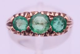 A 9 ct gold three-stone emerald ring. Ring size M. 3.6 grammes total weight.