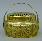 A Chinese brass pierced-topped swing-handle censer. 15 cm wide.