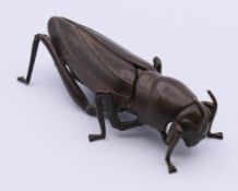 An articulated bronze model of a grasshopper. 8 cm long.