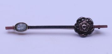 An unmarked gold bar brooch with Tudor rose and oval light blue stone. 5.7 cm long. 5.