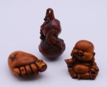 Three wooden carvings (a gourd with a tiger, a laughing Buddha and a foot with spiders).