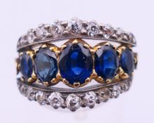 An unmarked gold, diamond and sapphire ring. Ring size M. 4.8 grammes total weight.