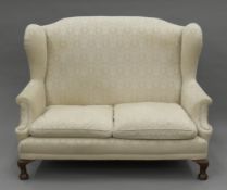 An early 20th century upholstered wing back settee. 140 cm wide.