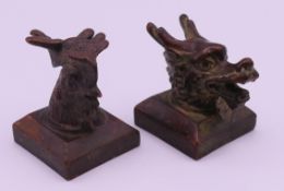 A pair of Chinese bronze seals, one with a dragon's head, the other a rooster's head.