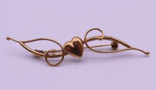 A 9 ct gold heart and scroll bar brooch. 5.5 cm long. 1.6 grammes.