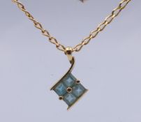 A 9 ct gold chain with a 9 ct gold and pale blue stone pendant.