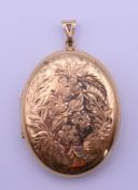 A 9 ct gold floral engraved oval locket. 4.7 cm high excluding suspension loop. 15.9 grammes.