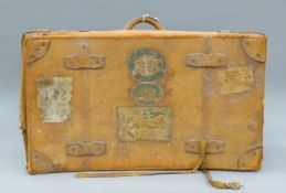 A vintage leather suitcase with various travel labels. 77 cm wide.