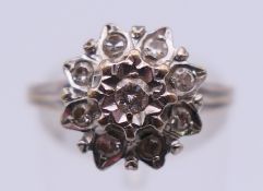 An unmarked white gold and diamond floral cluster ring. Ring size N/O. 3.9 grammes total weight.