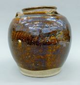 A Chinese Yuan Dynasty treacle-glazed pottery storage jar with four suspension lugs. 25 cm high.