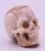 A carved antler skull. 3 cm high.