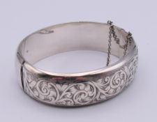 An engraved silver bangle form bracelet. 2 cm high, 5.8 cm internal diameter. 27.5 grammes.