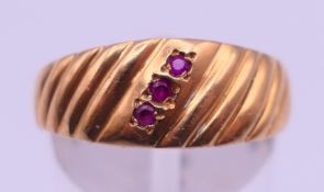 An unmarked gold three-stone ruby ring. Ring size Q/R. 3.7 grammes total weight.