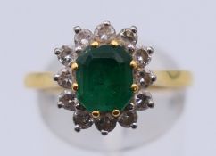 An 18 ct gold, emerald and diamond ring. Ring size Q. 3.6 grammes total weight.
