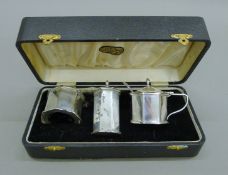 A cased three-piece silver cruet set with plated salt spoon. The case 23 cm wide. 156.3 grammes.