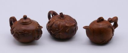 Three Oriental wooden models of teapots. The largest 8 cm long.