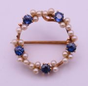 A 14 ct gold, sapphire and pearl circular brooch. 2 cm diameter. 2.7 grammes total weight.