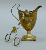 A Georgian silver cream jug and a pair of broken sugar tongs. The former 12 cm high. 117.6 grammes.