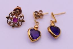 A pair of amethyst heart shaped earrings and a single ruby earring. Amethyst earrings 2 cm high.